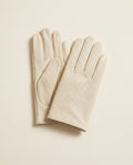 Pair of cream perforated driving gloves on a cream studio backdrop
