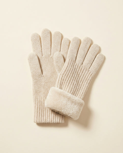 Pair of oatmeal ribbed winter gloves with a fold-back cuff on a cream studio backdrop