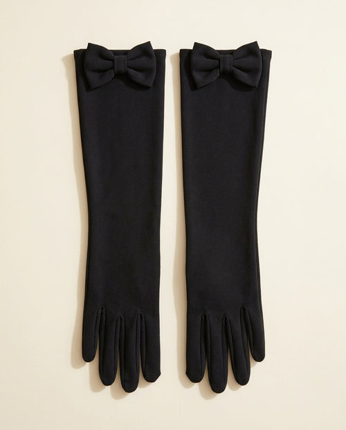 Pair of long black gloves with a bow at the top cuff on a cream studio backdrop
