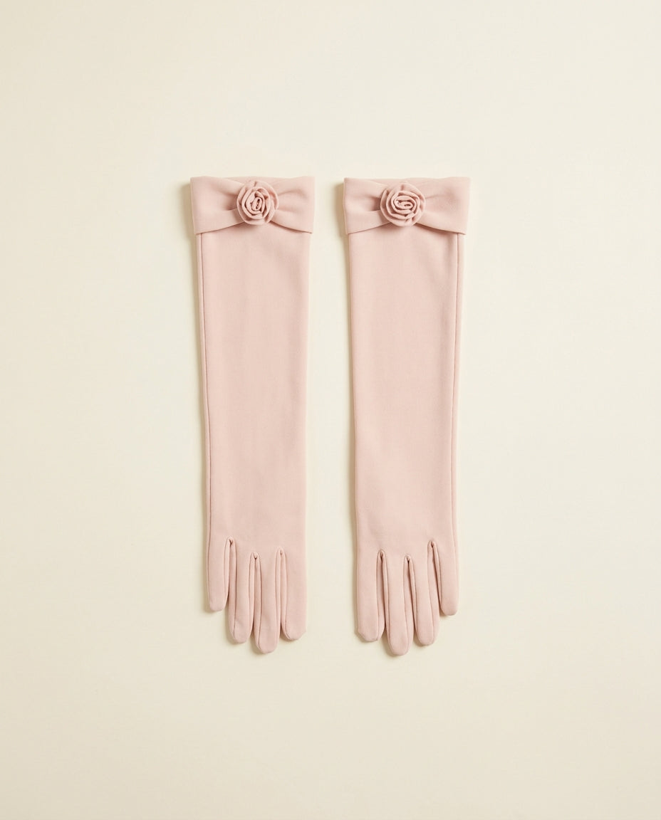 Pair of blush above-elbow opera gloves with a small rosette detail on a cream studio backdrop
