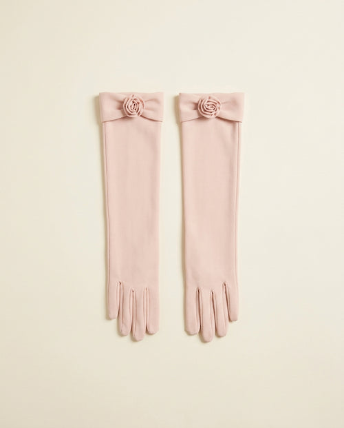 Pair of blush above-elbow opera gloves with a small rosette detail on a cream studio backdrop