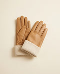 Pair of camel gloves with a contrast cream cuff on a cream studio backdrop