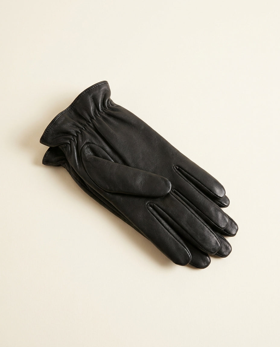 Pair of sleek black gloves with a gathered ruched wrist on a cream studio backdrop