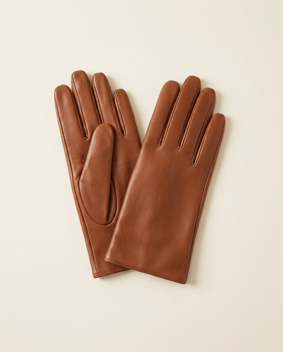 Pair of cognac fitted gloves with a short cuff on a cream studio backdrop
