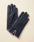 Pair of navy driving gloves with cream trim on a cream studio backdrop