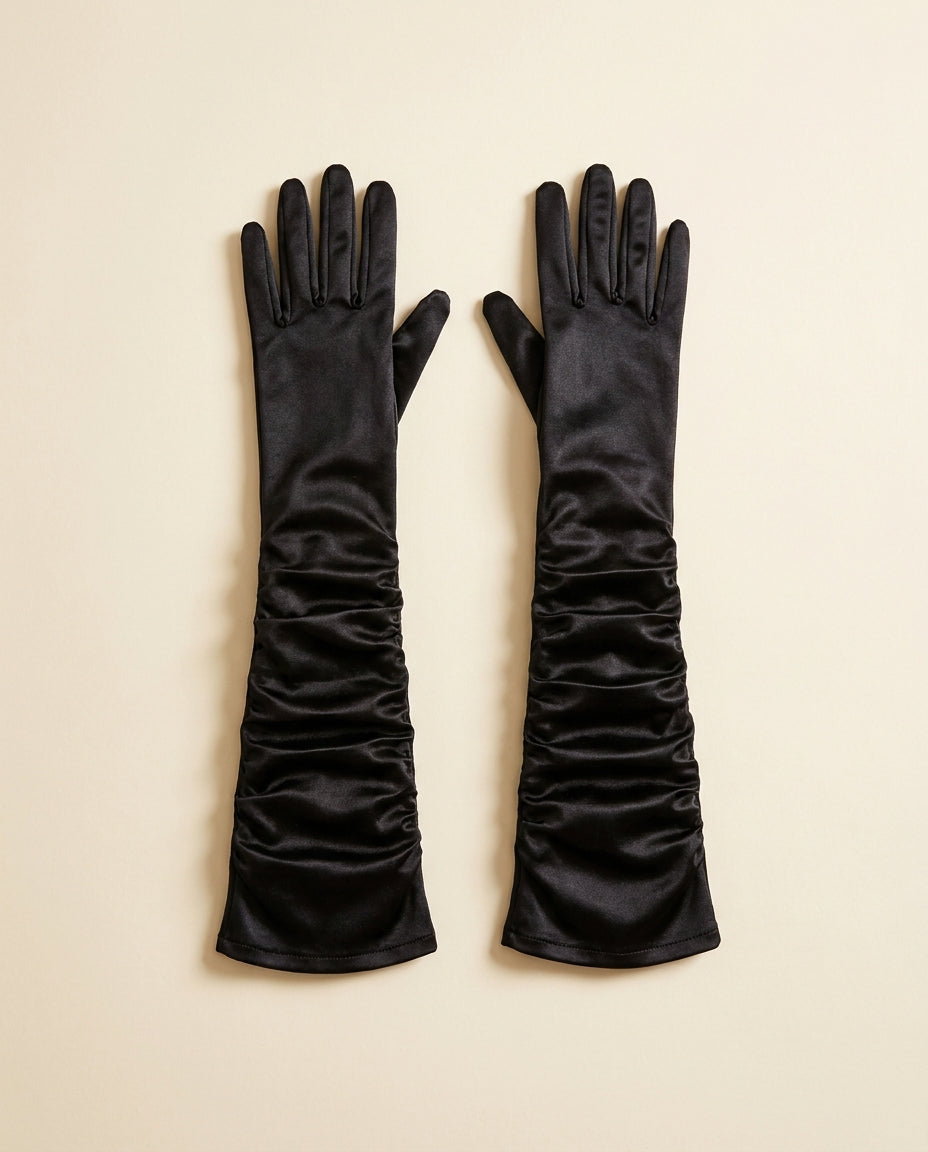 Pair of long black gloves ruched along the arm on a cream studio backdrop