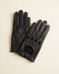 Pair of black open-knuckle driving gloves with a snap strap on a cream studio backdrop
